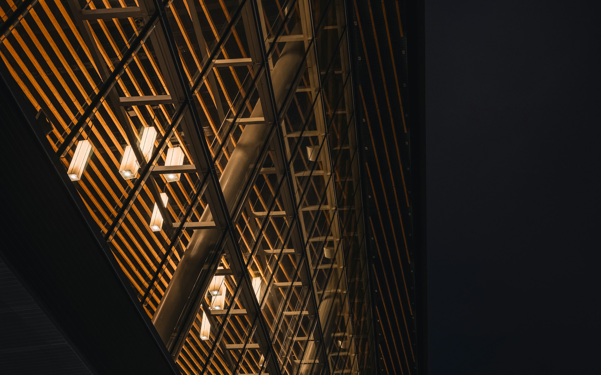 A timber-clad civic building lit by Vigorous fixtures after dark.